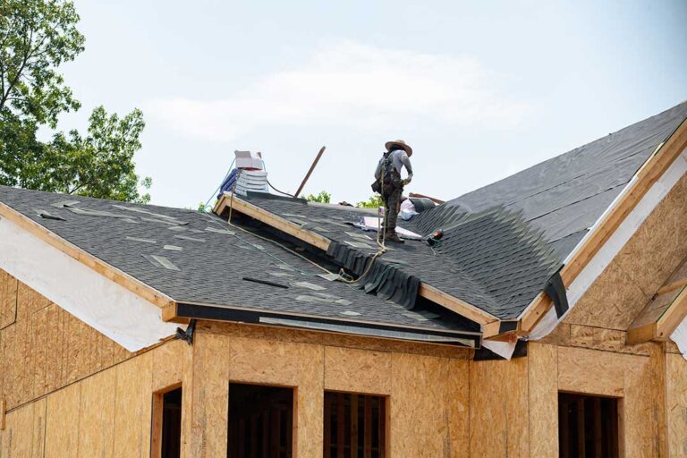 A residential home with a pitched roof beside a low-slope addition after light snowfall.